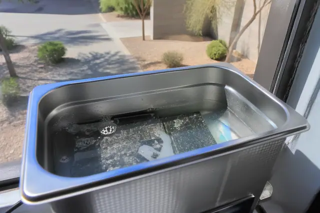 Circuit board submerged in an ultrasonic cleaning tank for water damage repair in Chandler, AZ.