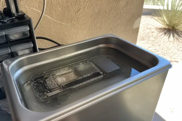 Smartphone logic board submerged in an ultrasonic cleaner for water damage repair in Mesa, AZ.