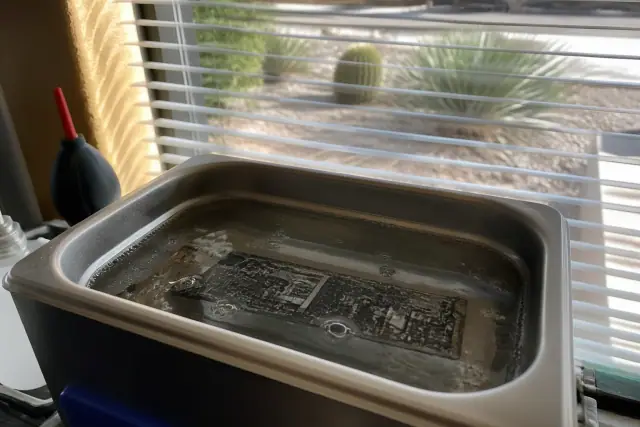 Circuit board submerged in an ultrasonic cleaner for iPhone repair in Phoenix, AZ.
