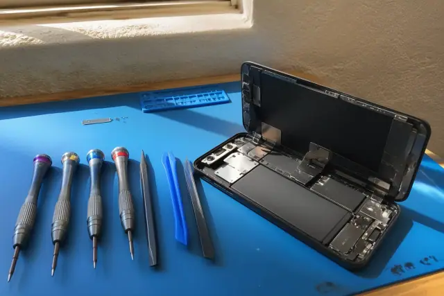 Opened smartphone with internal components on a workbench for water damage repair in Phoenix, AZ.