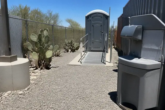 ADA-compliant portable toilet with ramp in a gravel utility corridor in Phoenix, AZ.