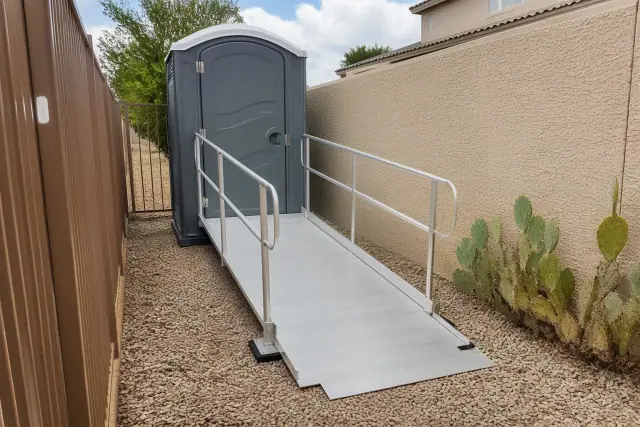 ADA-compliant portable toilet with an aluminum ramp on a gravel path in a residential area of Surprise, AZ.