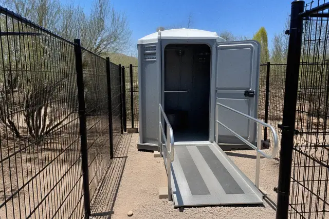 ADA-compliant portable toilet with an extended ramp on a job site in Phoenix, AZ.