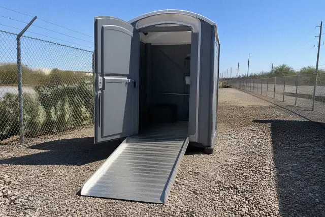 ADA-compliant portable toilet with an extended ramp on a gravel site in Chandler, AZ.