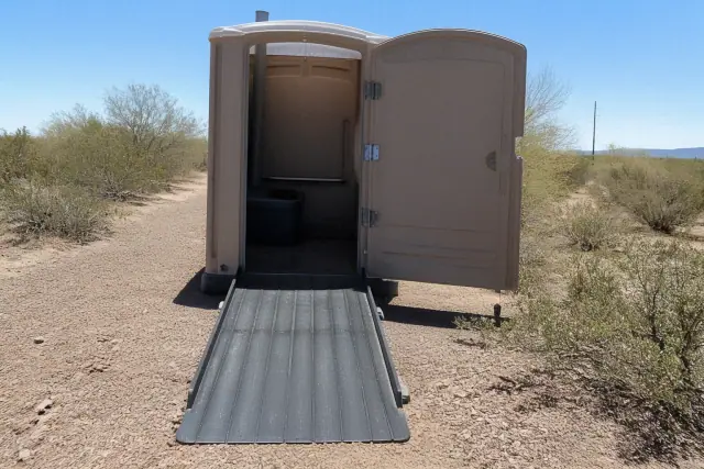 ADA-compliant portable toilet with an access ramp in a desert utility corridor in Buckeye, AZ.