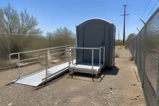 ADA-compliant portable toilet with ramp on a gravel maintenance path in Phoenix, AZ.