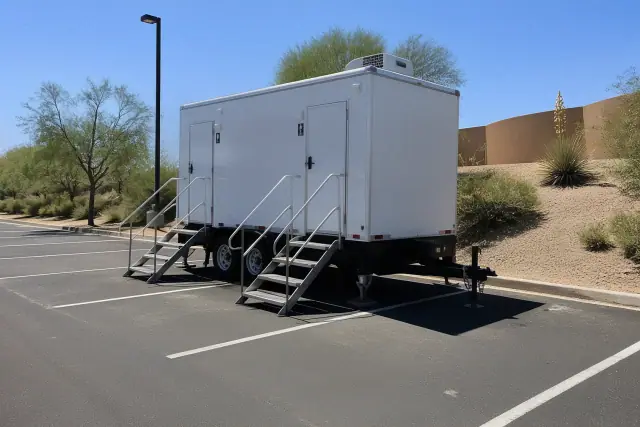 Luxury ADA restroom trailer leveled on an asphalt parking lot with desert landscaping in Phoenix, AZ.