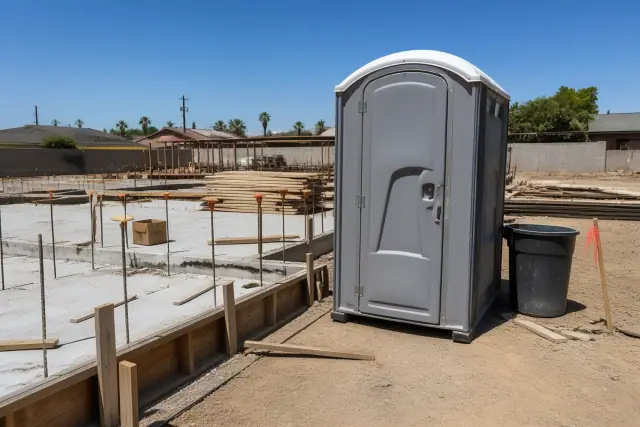 Portable sanitation unit on a construction site with exposed rebar and concrete slab in Phoenix, AZ.