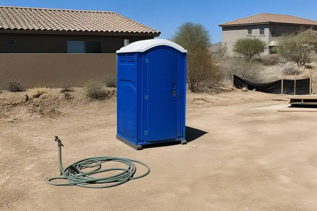 Blue portable toilet on a dirt patch at a construction site in Peoria, AZ.