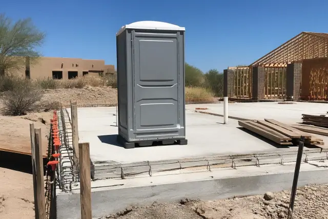 Portable toilet on a construction site concrete slab with exposed rebar in Scottsdale, AZ.
