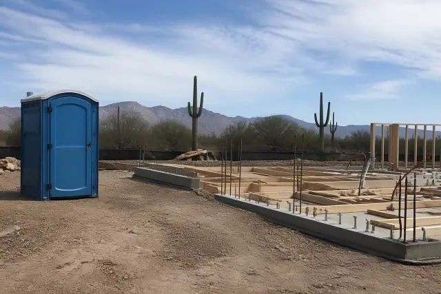 ADA portable toilet at a construction site with concrete foundation and rebar in Phoenix, AZ.