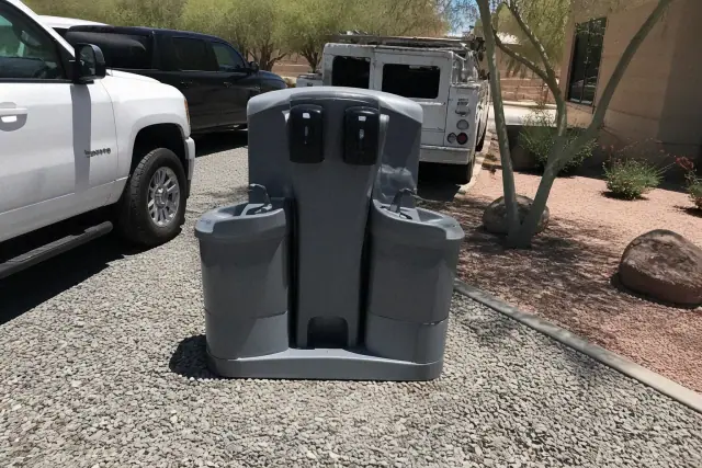 Dual handwashing station and service vehicles on a crushed stone surface in Phoenix, AZ.