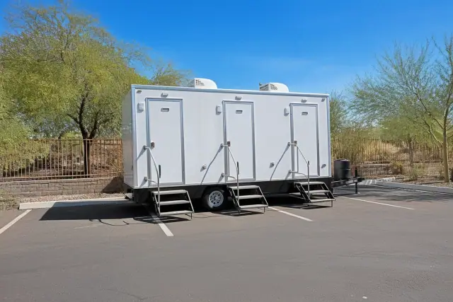 Luxury restroom trailer parked on an asphalt lot with desert landscaping in Phoenix, AZ.
