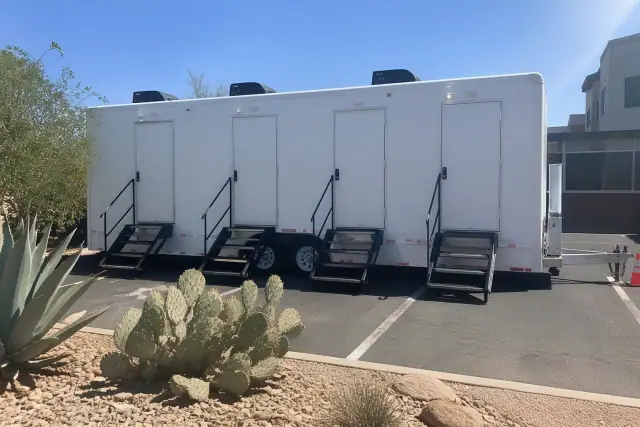 Luxury restroom trailer parked on an asphalt lot with desert landscaping in Phoenix, AZ.