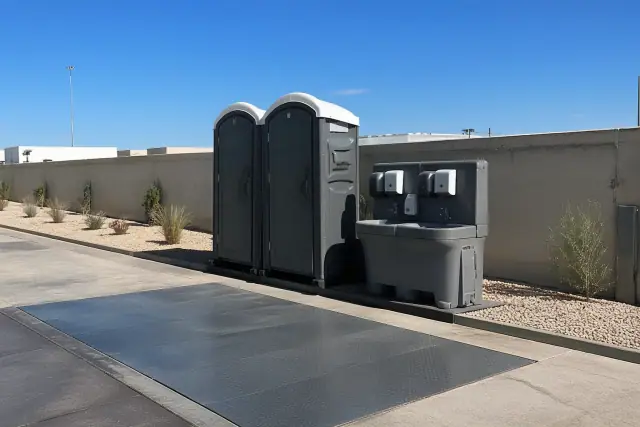Portable toilet and wash station set up on a concrete shipping apron at a jobsite in Phoenix, AZ.