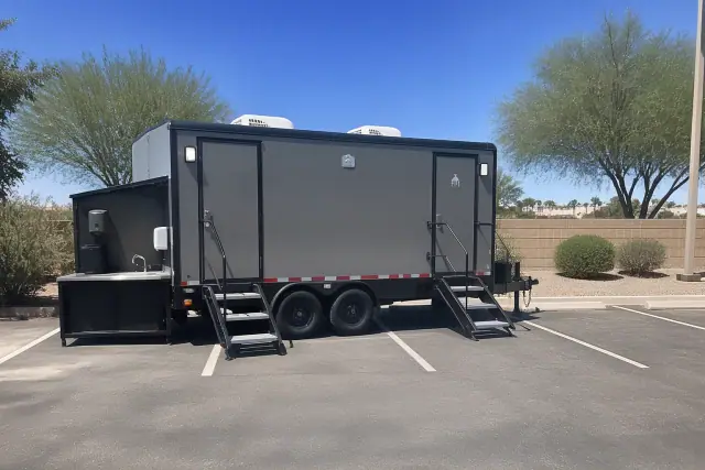 Luxury restroom and shower trailer parked on an asphalt lot with desert landscaping in Phoenix, AZ.