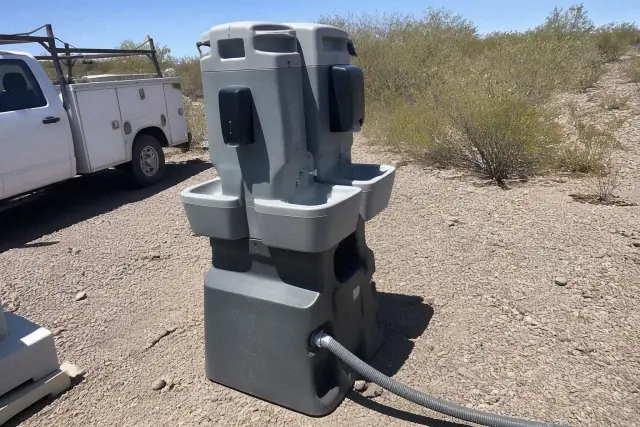 Dual handwashing station on a gravel site next to service vehicles in Peoria, AZ.
