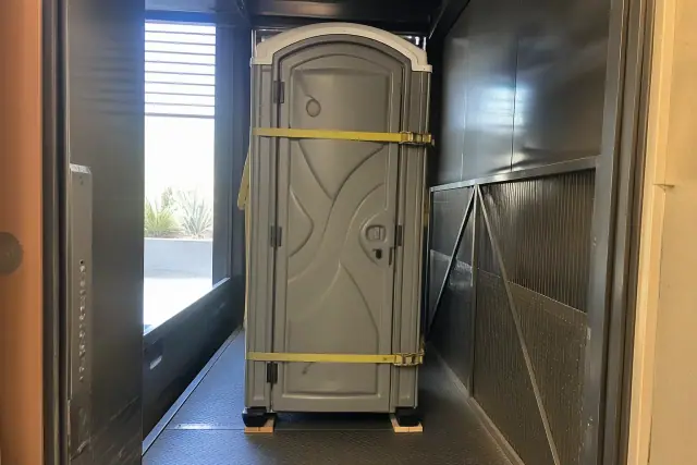 Narrow-profile portable toilet unit inside a high-rise service elevator at a construction site in Phoenix, AZ.