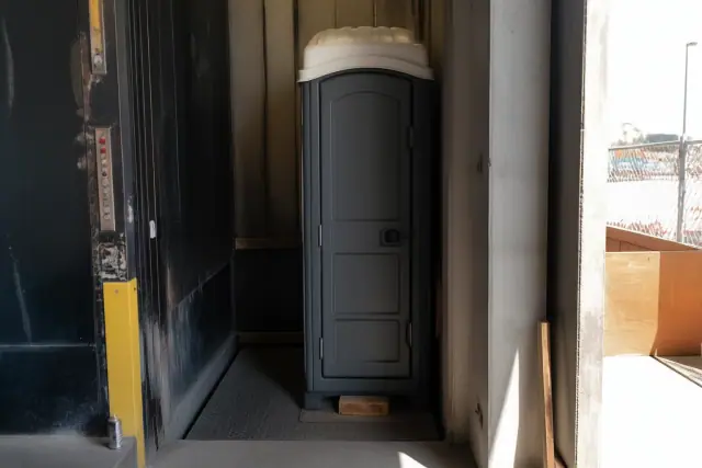 Narrow-profile portable restroom unit for construction crews in an industrial lift bay in Phoenix, AZ.
