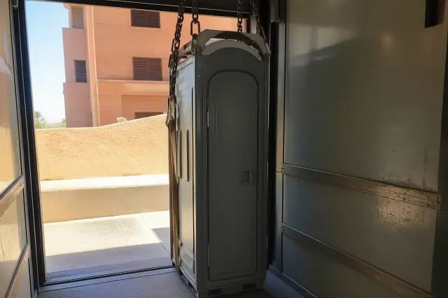Narrow-profile portable restroom unit inside a freight elevator at a job site in Tempe, AZ.