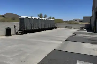 Portable toilets lined up on a concrete shipping dock at a jobsite in Phoenix, AZ.