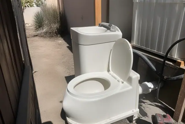 Combined sink-toilet unit on a desert jobsite in Phoenix, AZ, set in a narrow utility path.