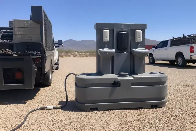 Portable toilet tanks and a handwashing station on a gravel jobsite in Phoenix, AZ.