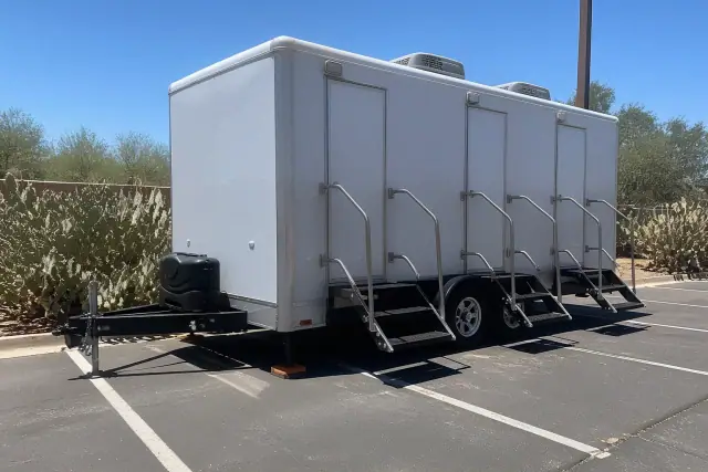 Luxury restroom trailer stabilized with shims on an asphalt parking lot in Mesa, AZ, under bright desert sun.