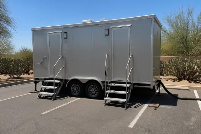 Luxury restroom trailer leveled on an asphalt parking lot with desert landscaping in Chandler, AZ.