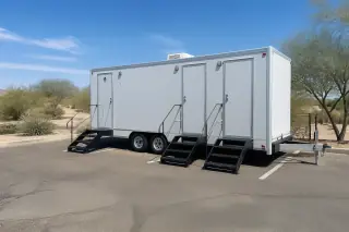 Luxury restroom trailer parked on a sun-bleached asphalt lot with xeriscape in Phoenix, AZ.