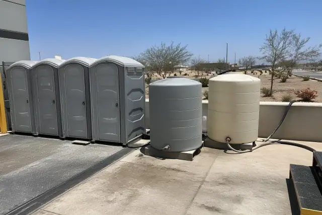 Portable toilets and holding tanks on a concrete loading dock at a jobsite in Phoenix, AZ.