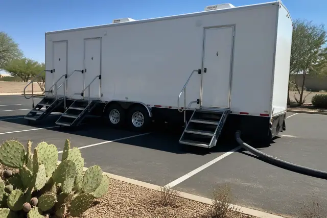 Luxury restroom trailer parked on an asphalt lot with desert landscaping in Goodyear, AZ.