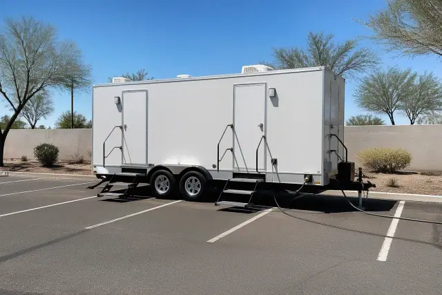 A luxury restroom trailer leveled on a sunlit asphalt parking lot at a jobsite in Phoenix, AZ.