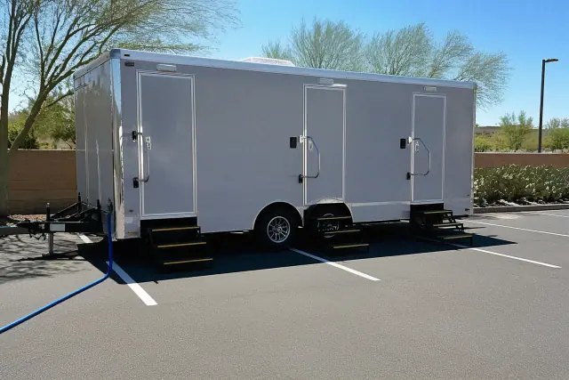 Luxury restroom trailer parked on asphalt with prickly pear cacti in Phoenix, AZ.