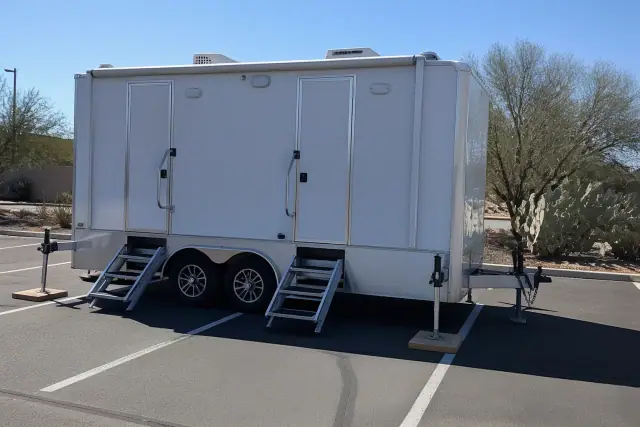 Luxury restroom trailer parked on an asphalt lot with desert landscaping in Surprise, AZ.