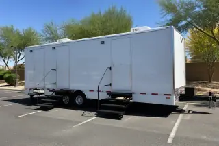 Luxury restroom trailer parked on an asphalt lot with desert landscaping in Phoenix, AZ.