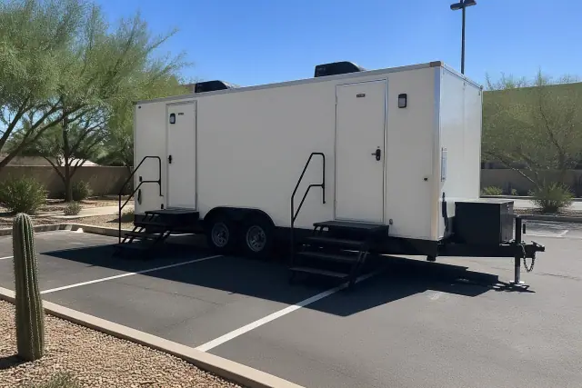 Luxury restroom trailer parked on an asphalt lot with desert landscaping in Phoenix, AZ.