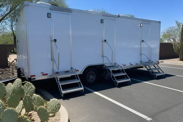 Luxury restroom trailer installed on a paved parking lot in Phoenix, AZ with nearby prickly pear cacti.