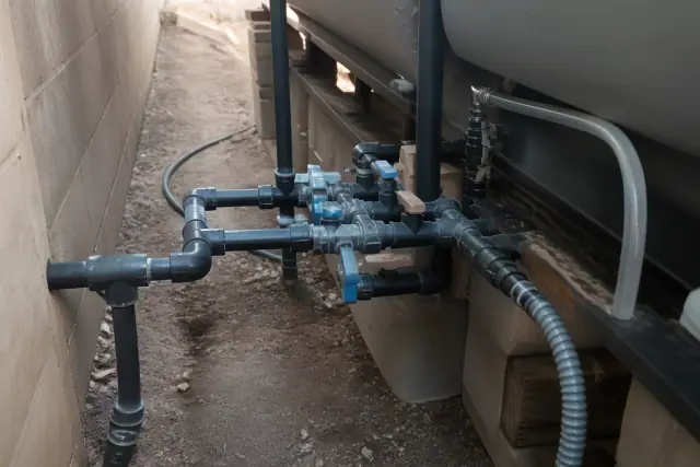 Plumbing manifold of an onboard freshwater and waste tank layout in a side yard in Phoenix, AZ.