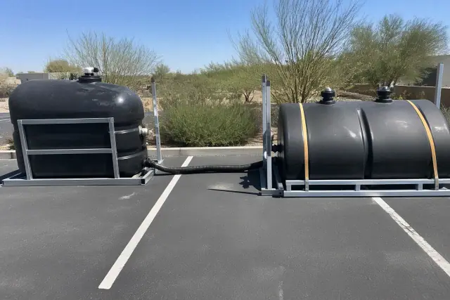 Portable waste holding tank equipment installed on asphalt in Phoenix, AZ, with visible connection hoses and service ports.