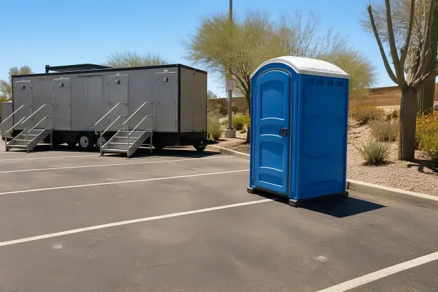 Porta potty placed on asphalt in a Phoenix, AZ right-of-way with desert landscaping and harsh sunlight.