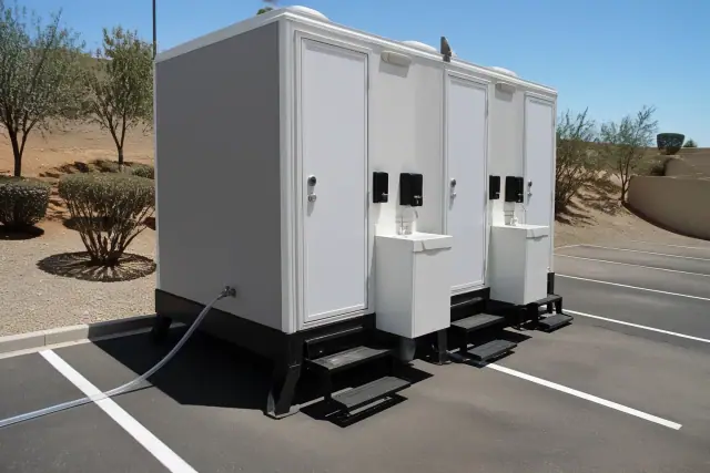 Portable toilets with sinks on an asphalt parking lot in Tempe, AZ.