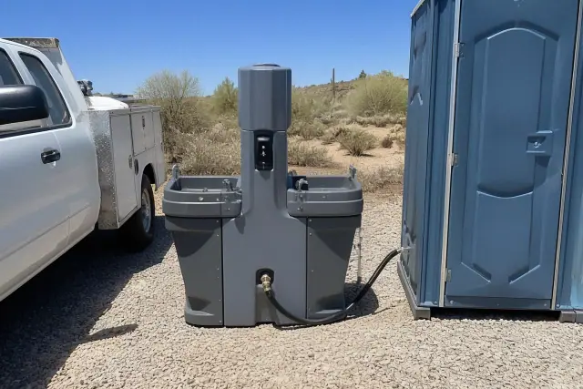 Portable handwashing station and toilets on a crushed stone surface in Peoria, AZ.