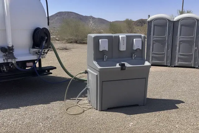 Portable toilets and a dual handwashing station on a crushed stone jobsite in Scottsdale, AZ.