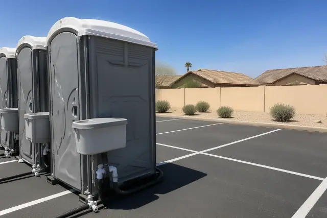 Portable toilets with sinks on an asphalt parking lot in Gilbert, AZ.