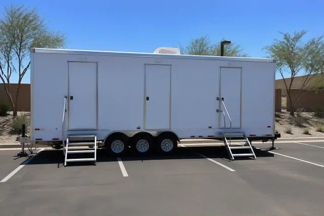 Luxury restroom trailer parked on an asphalt lot with desert xeriscaping in Phoenix, AZ.