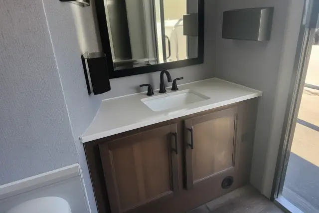Interior sink and vanity of a luxury restroom trailer parked on an asphalt lot in Phoenix, AZ.
