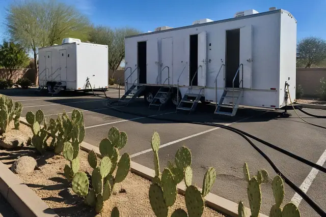 Luxury shower trailers parked on an asphalt lot with prickly pear cacti in Phoenix, AZ.