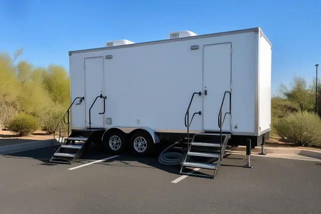 Luxury restroom trailer parked on asphalt with desert vegetation in Tempe, AZ.