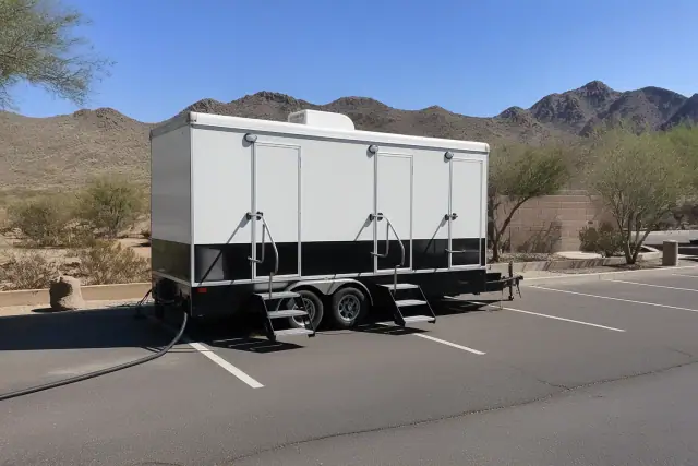 Luxury restroom trailer on a paved parking lot in Buckeye, AZ, with mountain silhouettes in the background.
